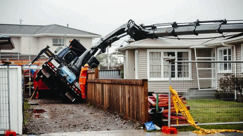A lines crane truck fully extending its crane while short jacked.