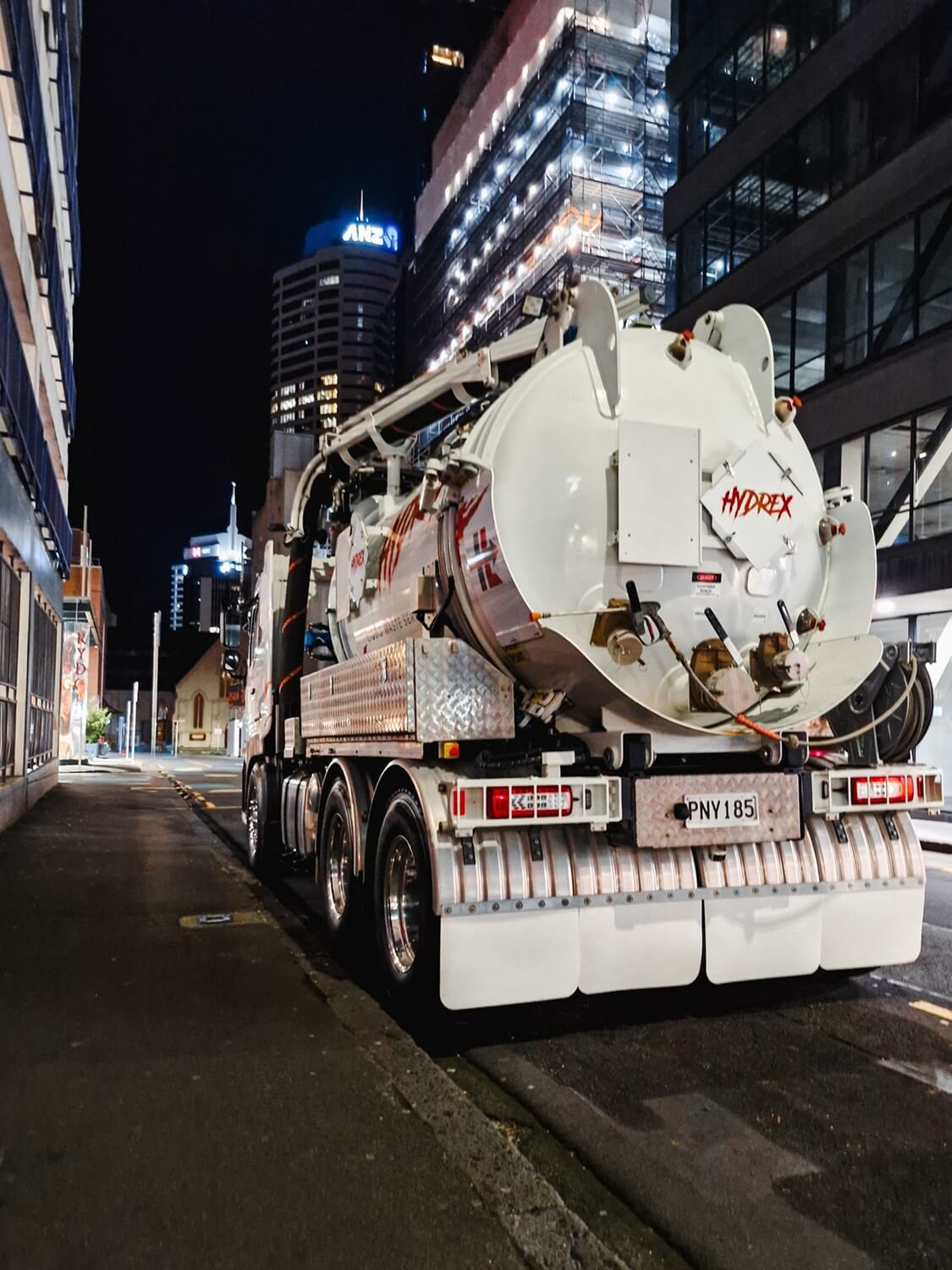 A hydro excavation truck with orange lighting on a dark night