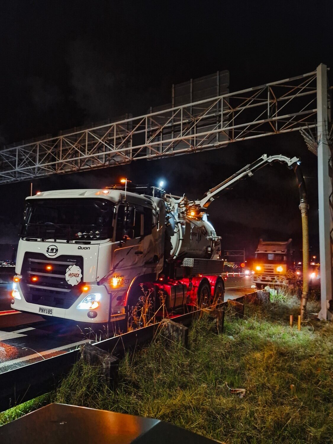 A hydro excavation truck with orange lighting on a dark night