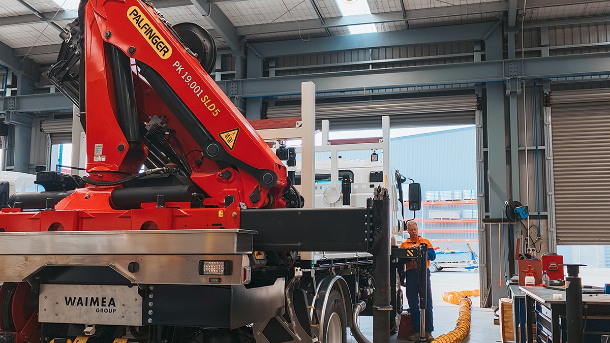 A lines crane truck fully extending its crane while short jacked.
