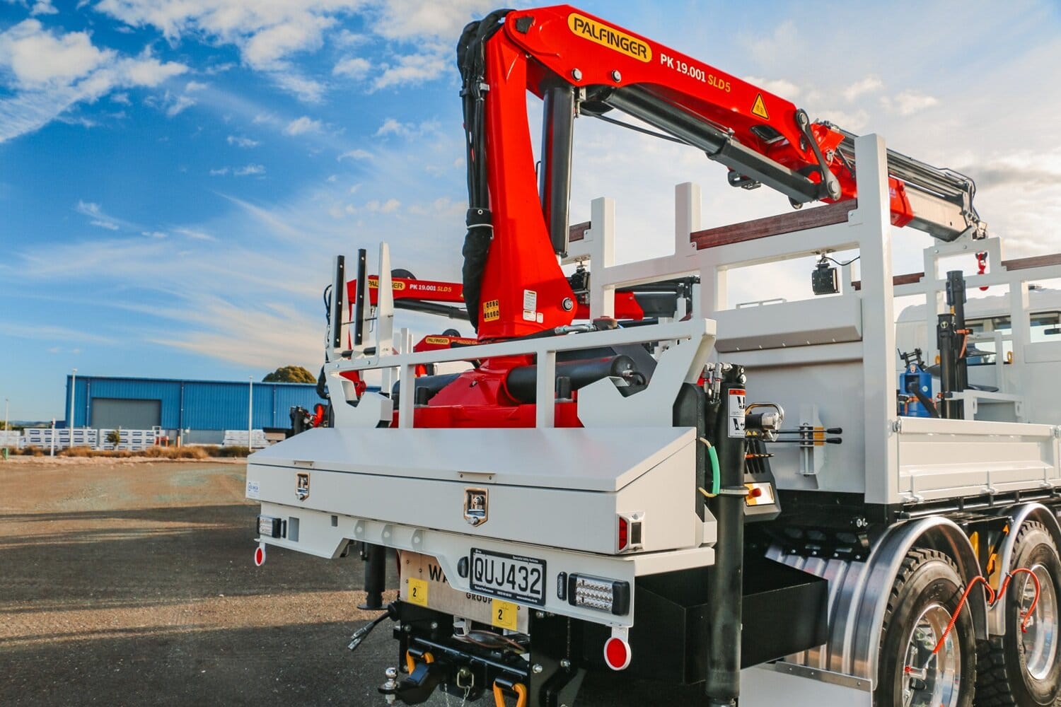 A salesman and a customer shaking hands standing in front of three lines crane trucks that are being handed over