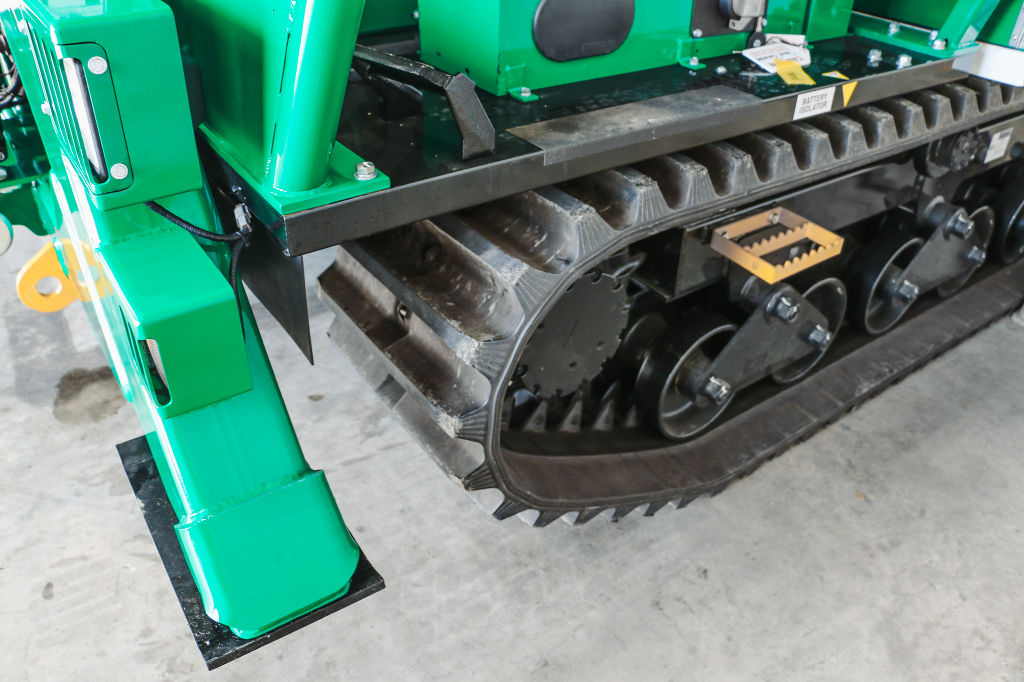 A specialist utility truck with tracks instead of wheels and a Versalift boom parked in a workshop with the boom stowed.