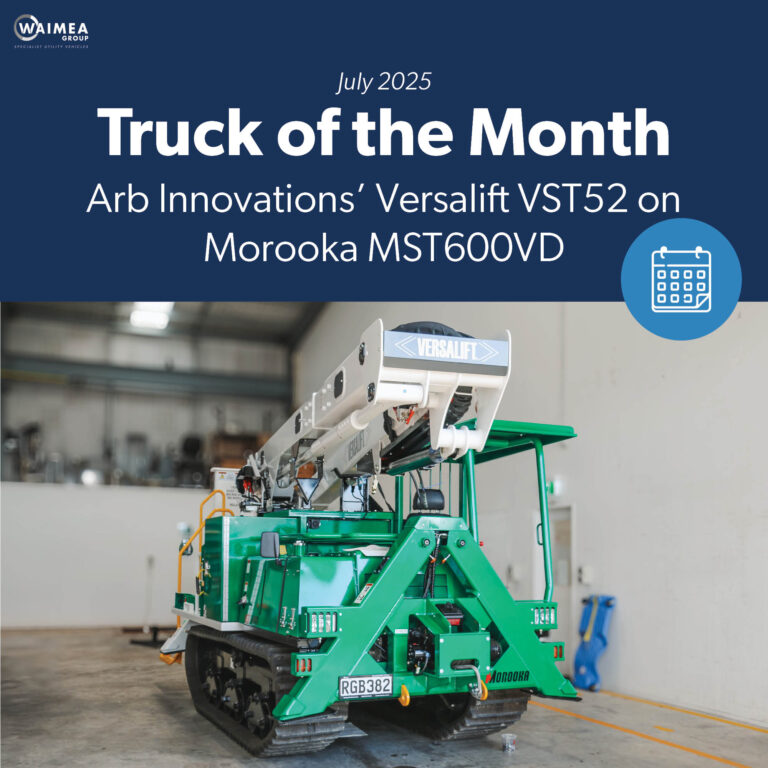 A specialist utility truck with tracks instead of wheels and a Versalift boom parked in a workshop with the boom stowed.