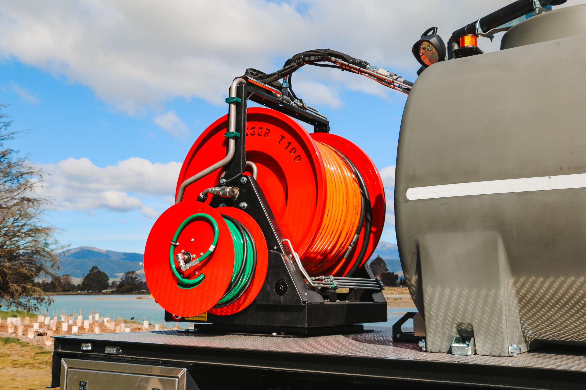 IMG_2928 A large utility truck parked on the grass in front of a body of water, equipped with jetting equipment, carrying a 6000L tank and two hose reels with a set of nozzles for jetting out drains and culverts.