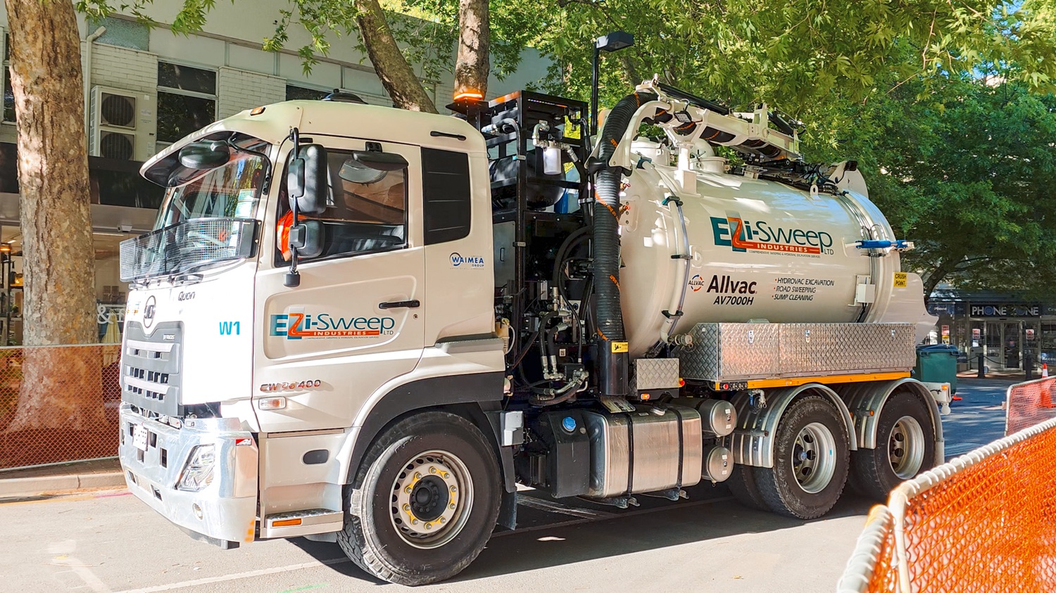 A man in hi-vis gear and a hard hat standing in front of an Allvac® AV7000H hydrovac truck and other drilling equipment on a construction site