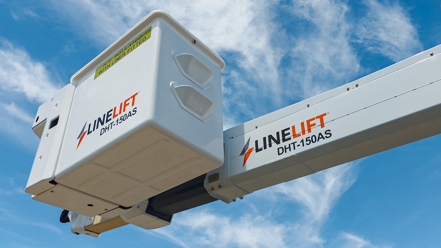 A vacuum tanker truck painted pale blue, with a large tank, side trays, and a compact chassis, parked in a green vineyard