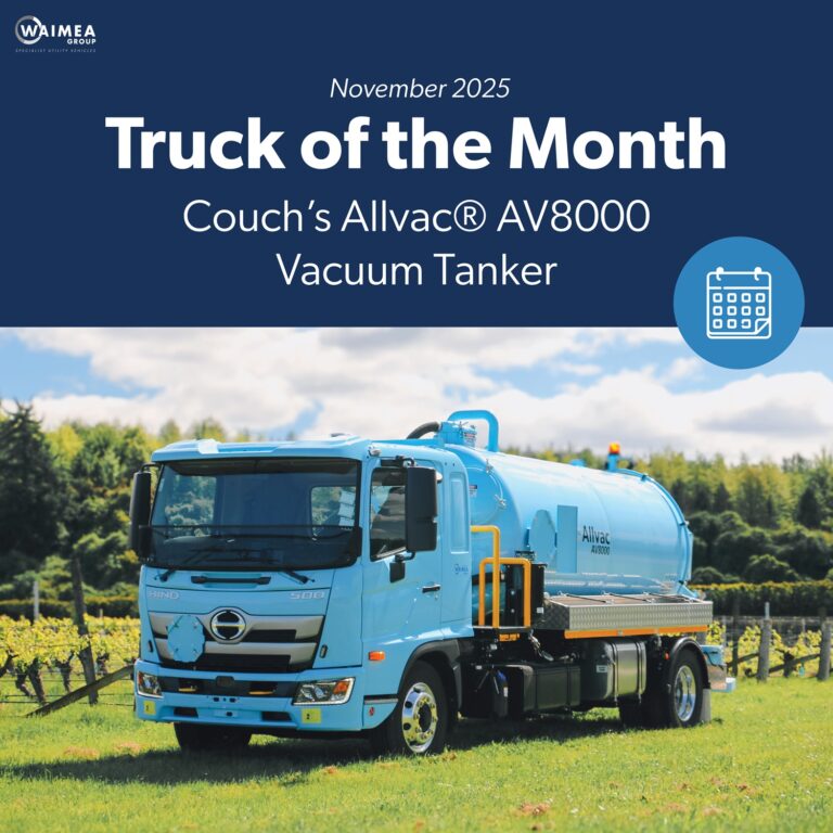 A vacuum tanker truck painted pale blue, with a large tank, side trays, and a compact chassis, parked in a green vineyard