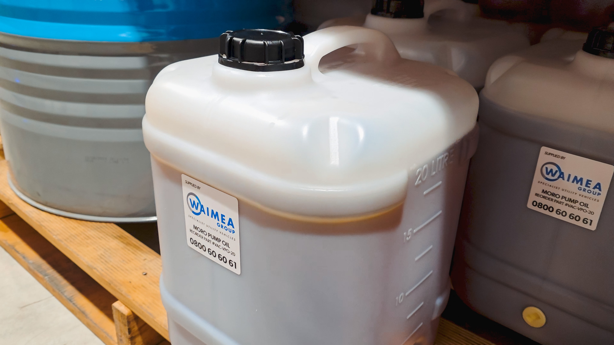 A man crouching next to a blue Moro Kaiser vacuum pump fitted on a vacuum tanker truck, talking to the camera.