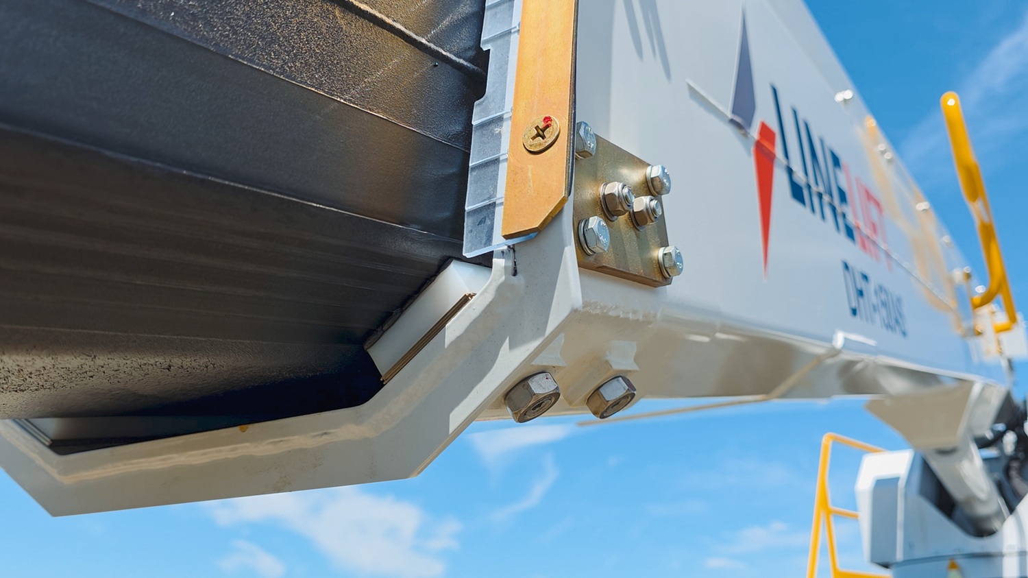 A man standing on a Linelift bucket truck in front of its insulated boom, explaining and pointing to the rear of the insulated boom