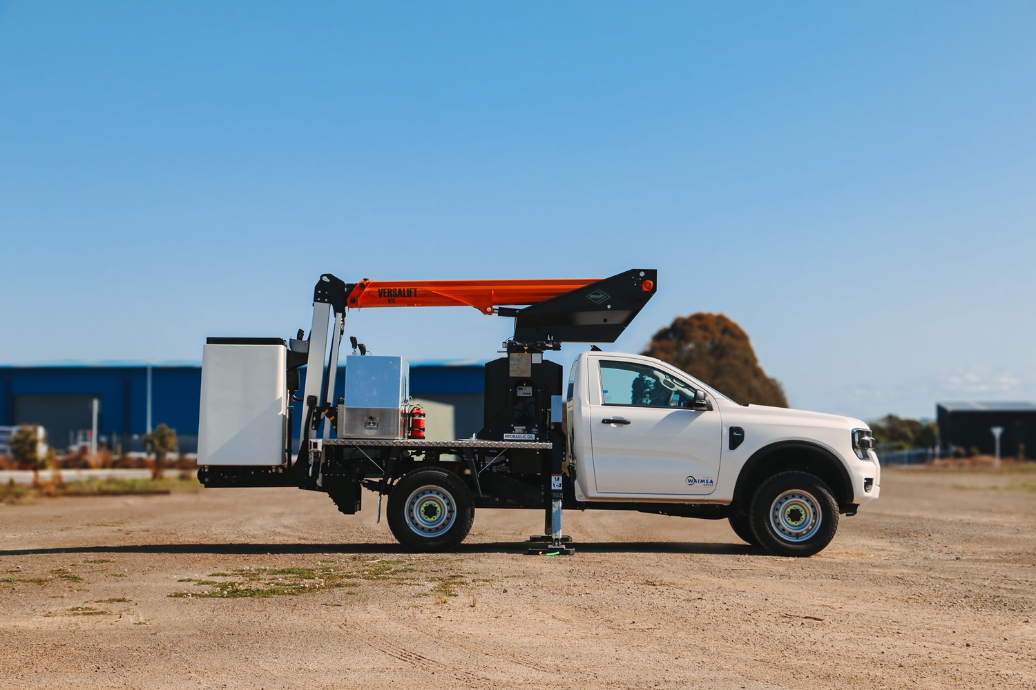 A compact white Ford Ranger ute with a Versalift crane and bucket mounted on the back for use in working at height, with toolboxes mounted on the deck.