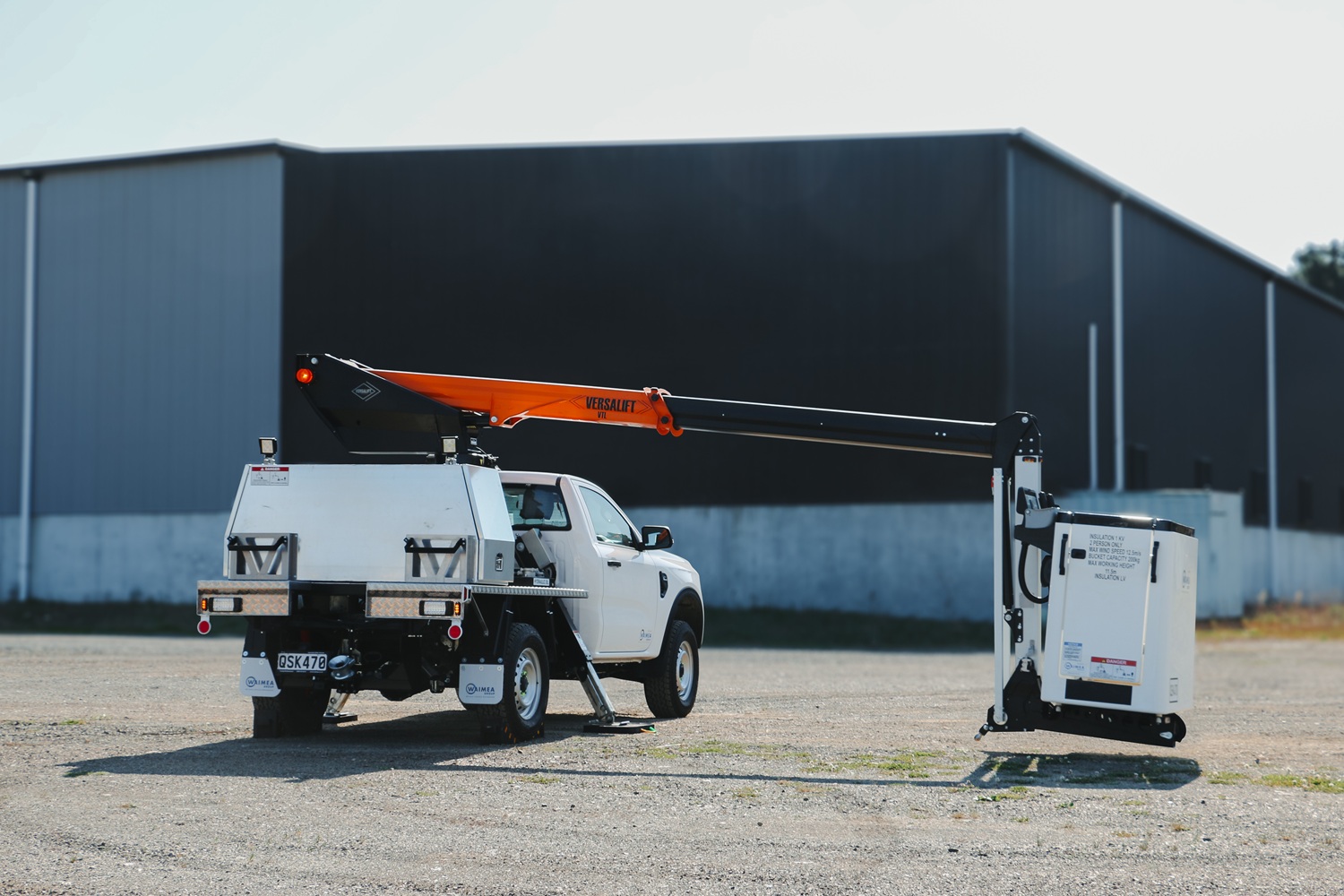 A compact white Ford Ranger ute with a Versalift crane and bucket mounted on the back for use in working at height, with toolboxes mounted on the deck.