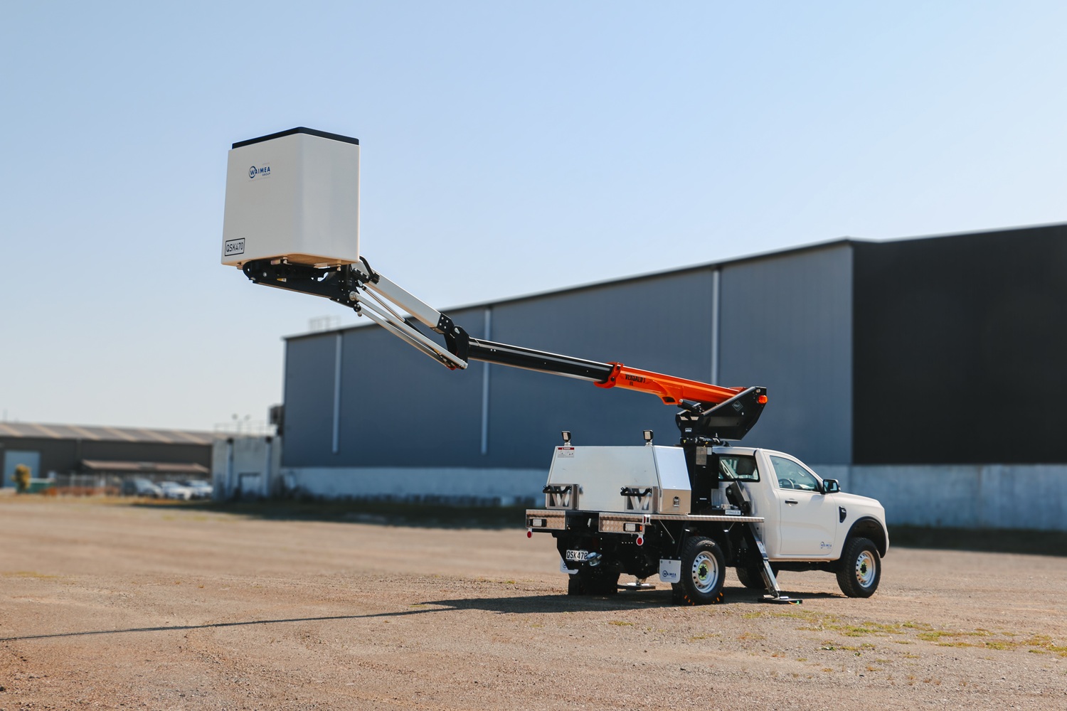 A compact white Ford Ranger ute with a Versalift crane and bucket mounted on the back for use in working at height, with toolboxes mounted on the deck.