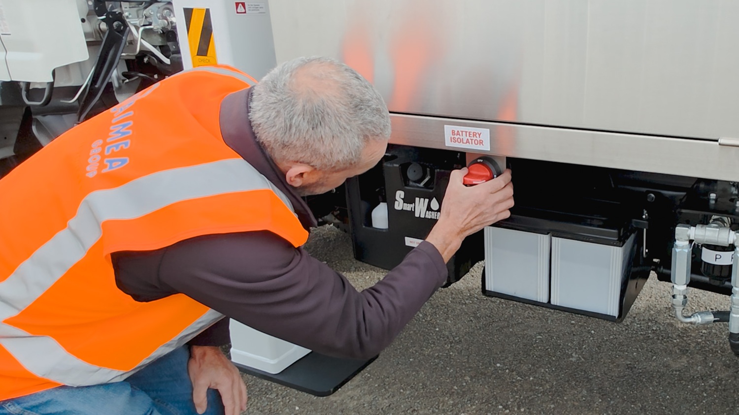 A man in a hi-vis vest stands in front of a white Linelift® bucket truck, which is parked in the background and has the boom and bucket extended into the foreground. The man is gesturing to the bucket.