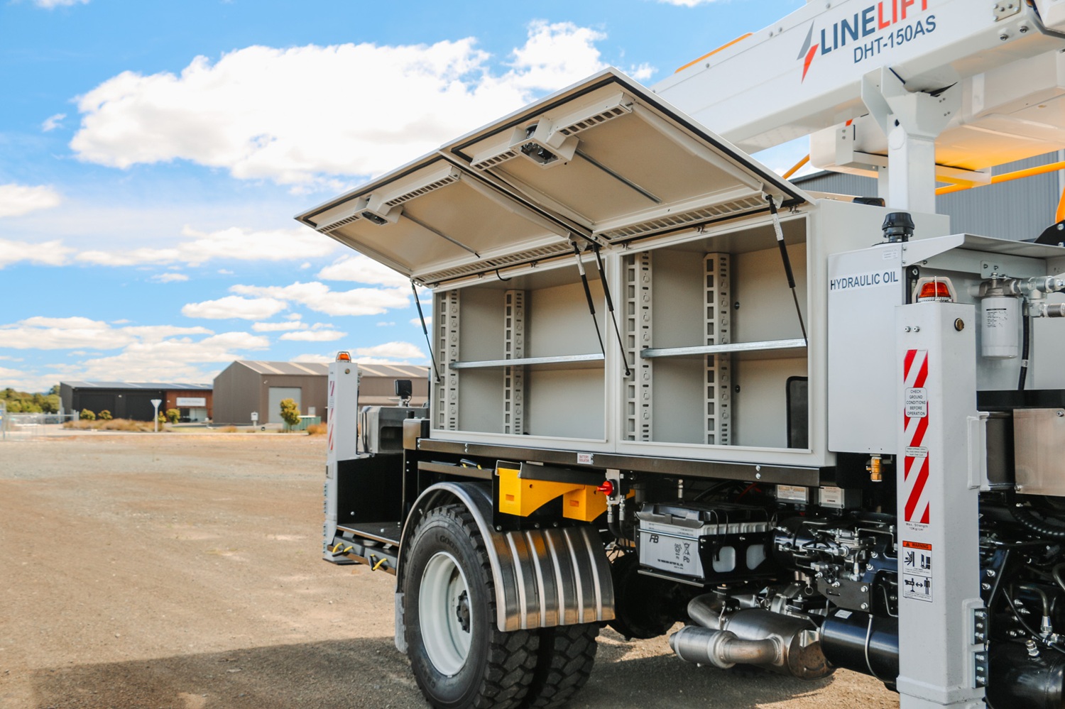 A white EWP truck with Linelift® branding set up in an open area, with the boom and bucket up and extending diagonally to the left.