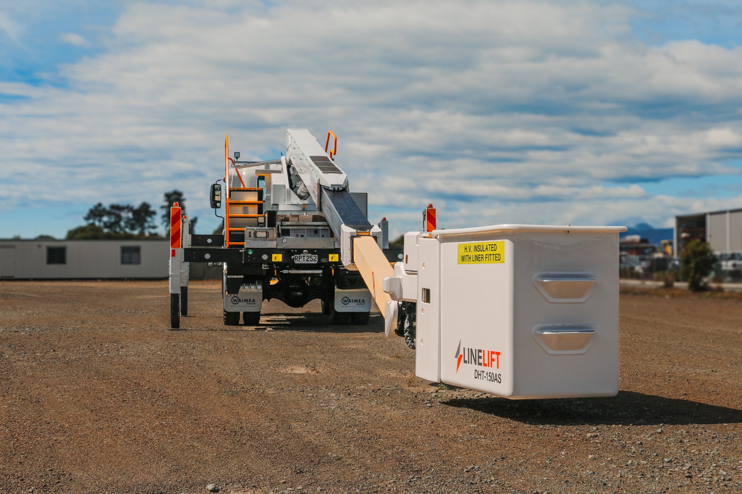 A white EWP truck with Linelift® branding set up in an open area, with the boom and bucket up and extending diagonally to the left.