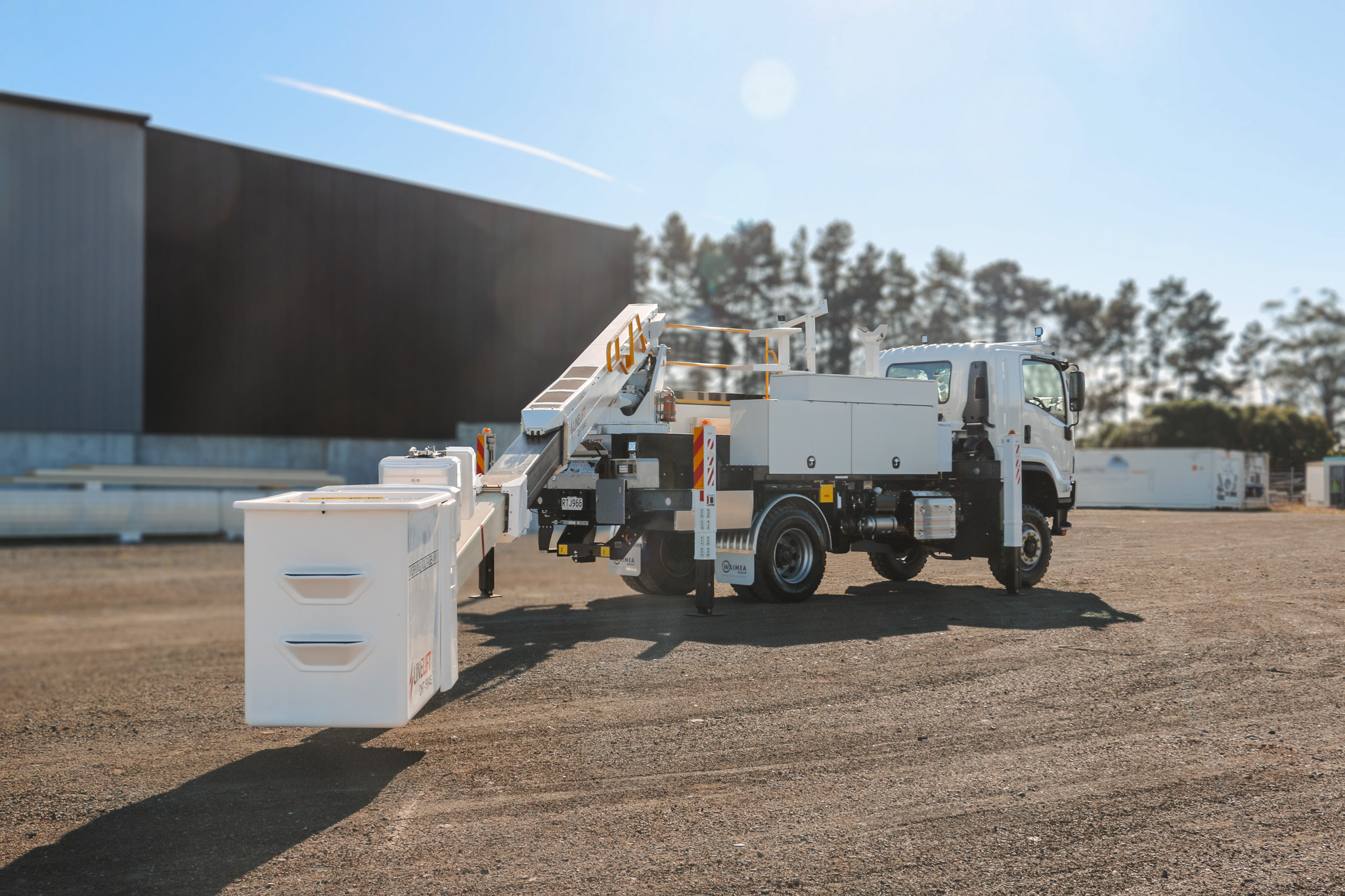 A white specialist elevated work platform truck parked on gravel, with a boom and bucket mounted on top with Linelift® branding and large toolboxes on the sides.