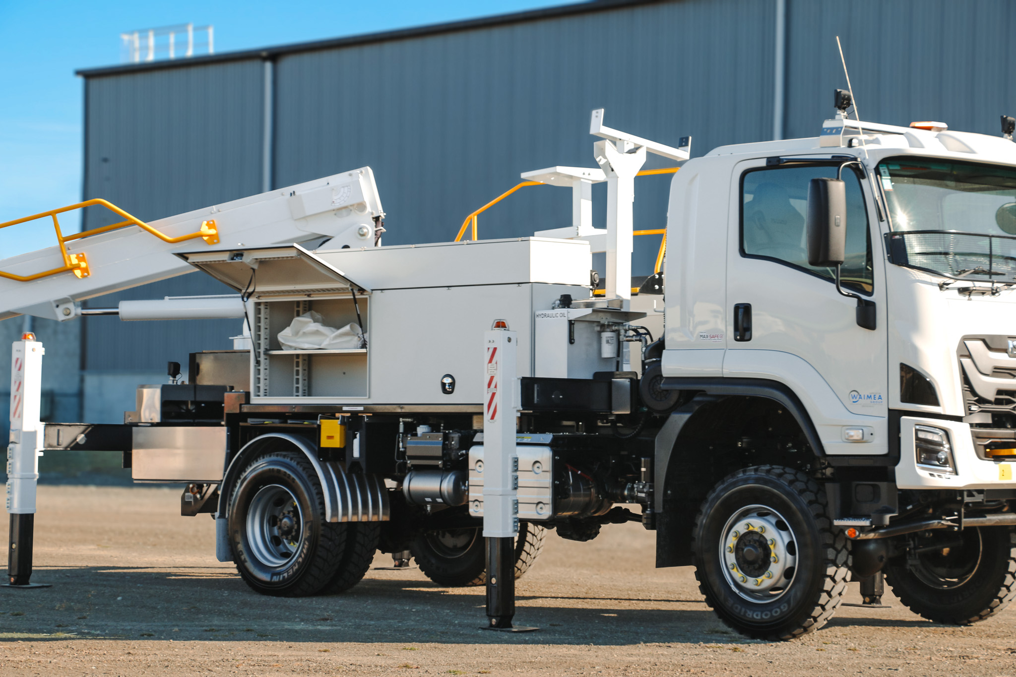 A white specialist elevated work platform truck parked on gravel, with a boom and bucket mounted on top with Linelift® branding and large toolboxes on the sides.