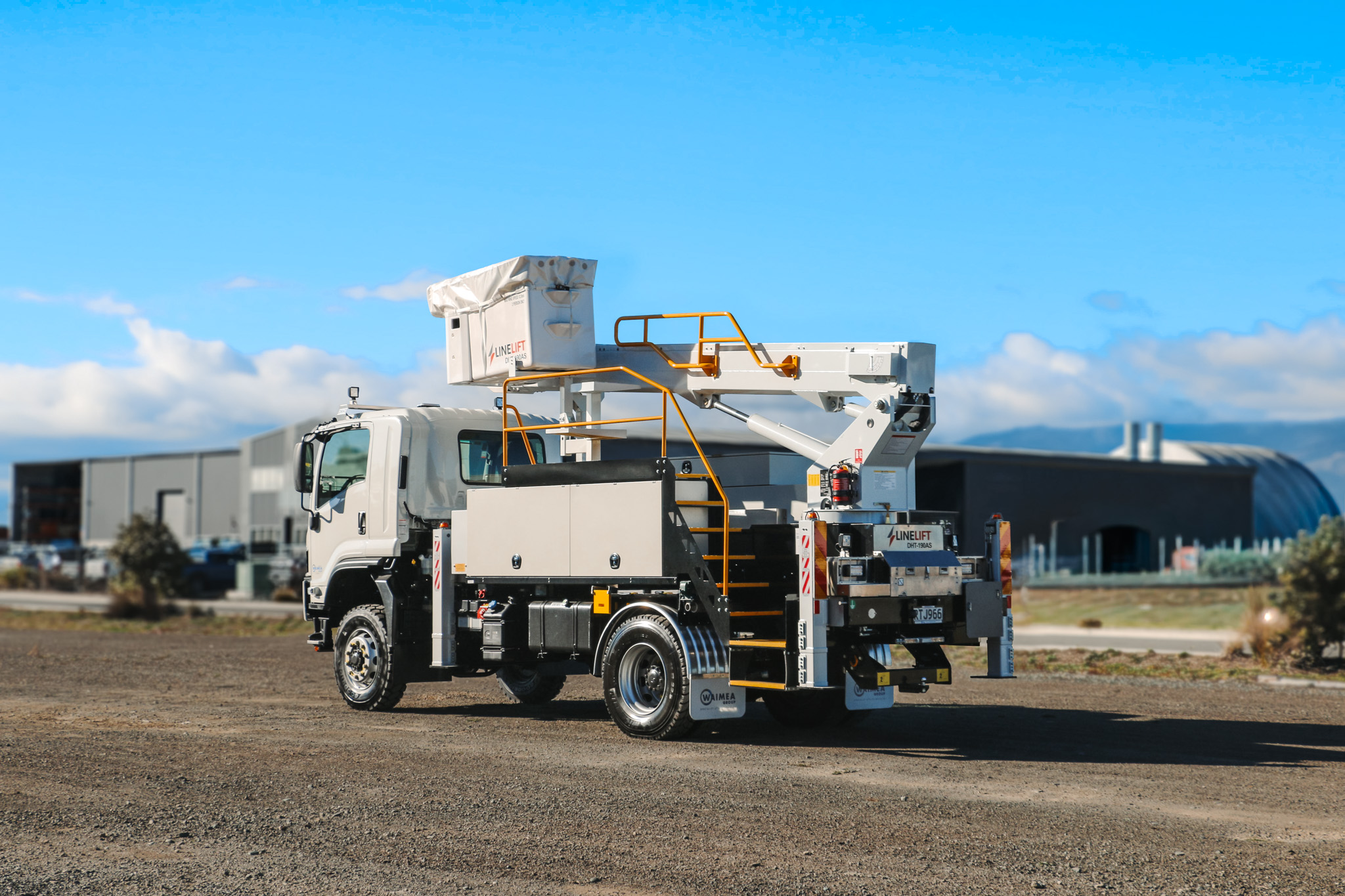 A white specialist elevated work platform truck parked on gravel, with a boom and bucket mounted on top with Linelift® branding and large toolboxes on the sides.